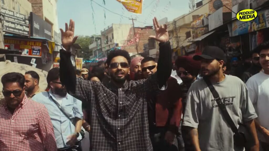 Navaan Sandhu raising hands in a crowded street bazaar in the Kath Lagda music video