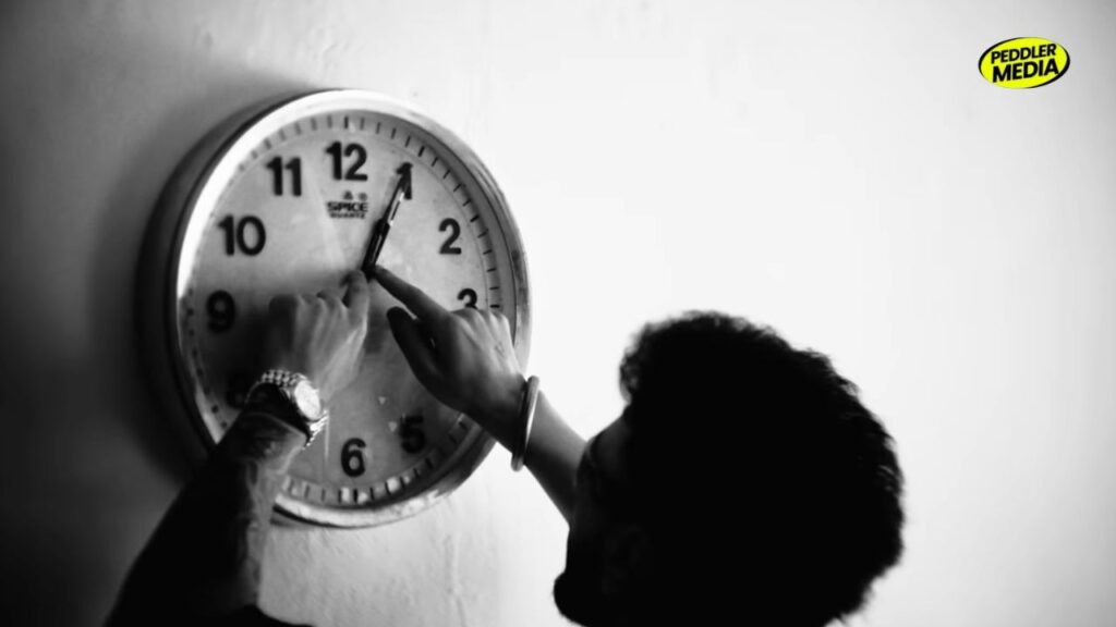 A person adjusting a wall clock in a symbolic scene from Navaan Sandhu's Kath Lagda music video
