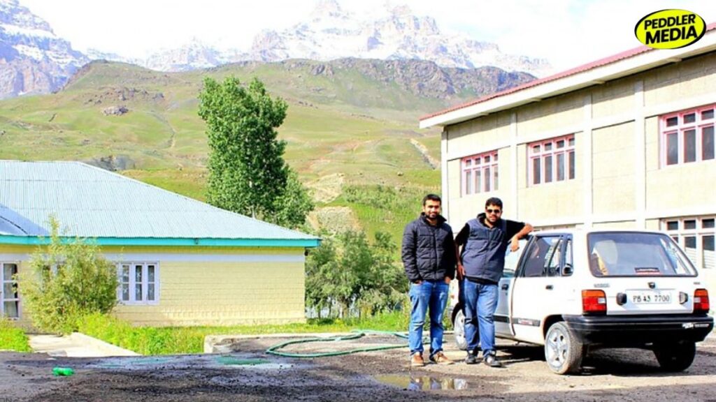 Two boys from Punjab leaning on their 1997 Maruti 800 PB 43 7700 with snow-capped Drass mountains in background during Leh trip
