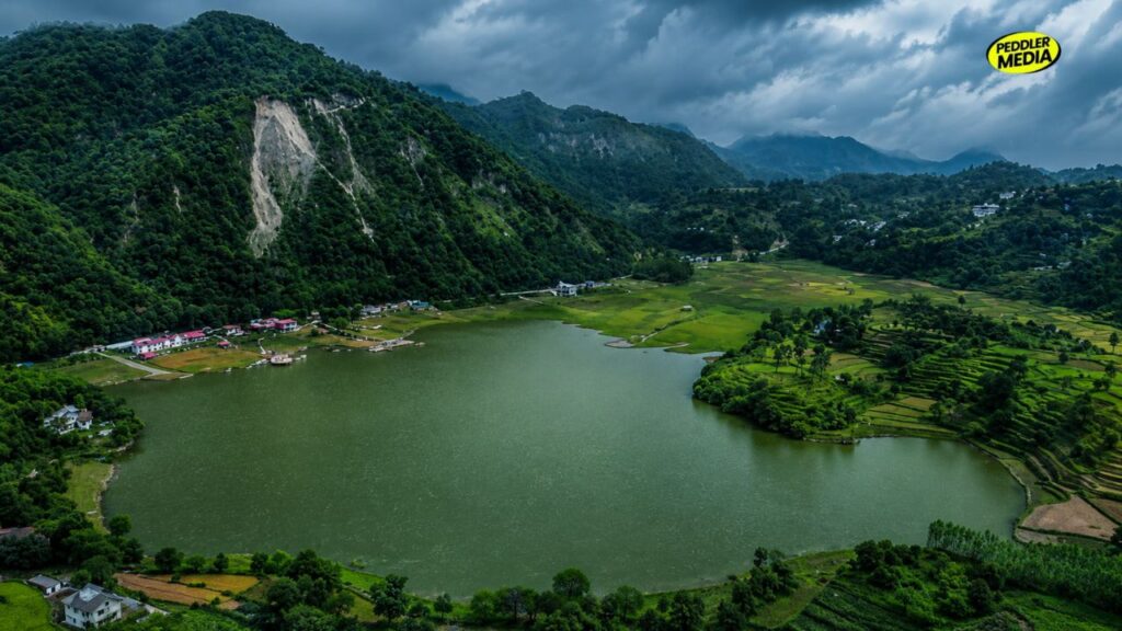 Breathtaking aerial drone view of Tikkar Taal lake nestled inside the lush green foggy Shivalik mountain ranges of Morni Hills during Haryana in monsoon.
