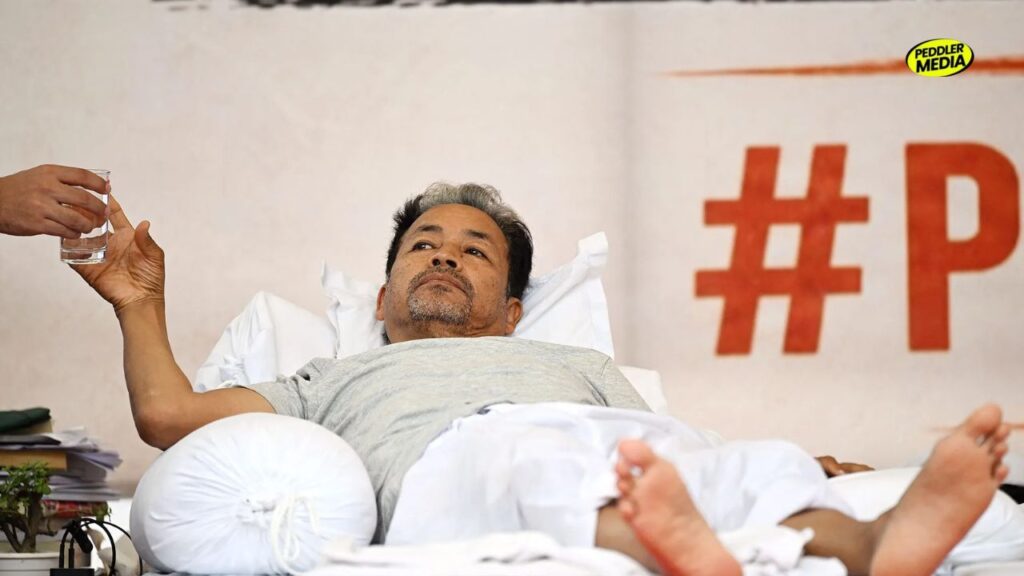 Sonam Wangchuk lies at the Jantar Mantar protest site as he is handed a glass of water