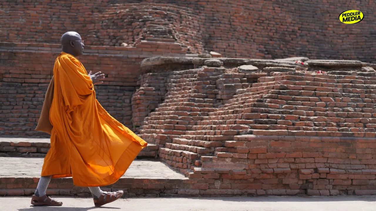 Buddhist monk walking beside ancient brick stupa ruins