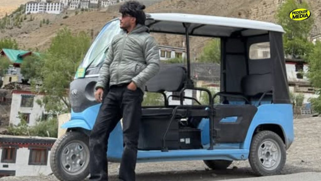 Sumit Prajapati posing next to his blue electric vehicle during his viral e-rickshaw to Spiti Valley mountain trip.