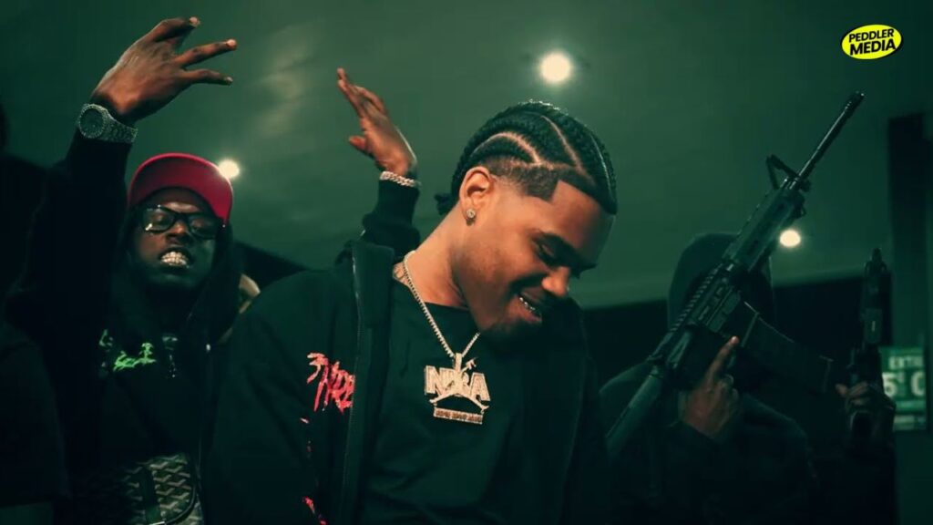 Rapper OG 3Three wearing an NBA chain pendant in a music video scene