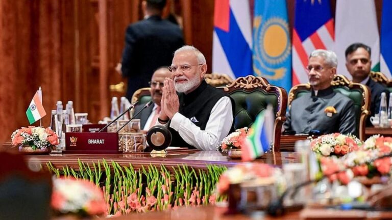 PM Narendra Modi sitting at the main desk welcoming leaders with folded hands at the BRICS Summit 2026 conference in New Delhi.