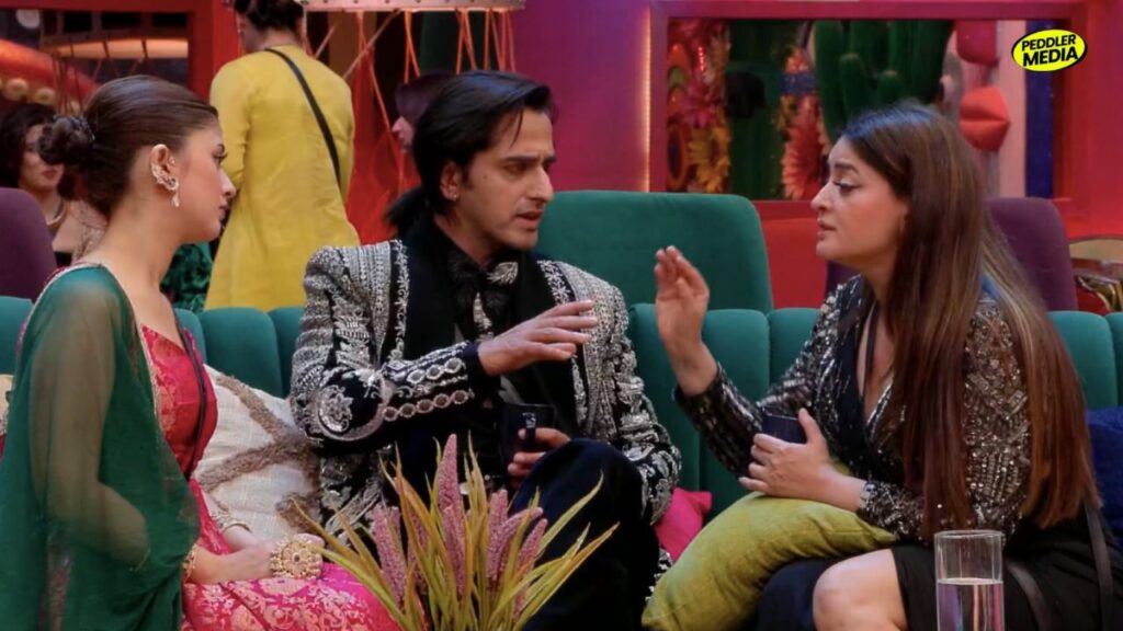 Bigg Boss latest episode contestants Arishfa Khan, Qazi Touqeer, and Mahhi Vij sitting on a green sofa.