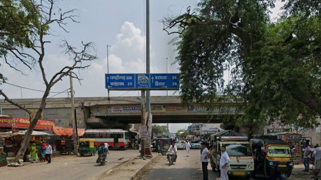 A state highway SH-10 route signboard to explore Haryana showing road distances toward Barwala, Hisar, and Fatehabad.