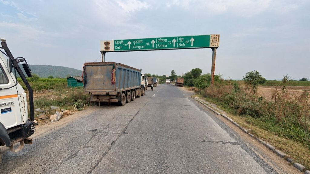 A state highway SH-13 route signboard to explore Haryana showing direction distances toward Nuh, Sohna, and Gurugram.