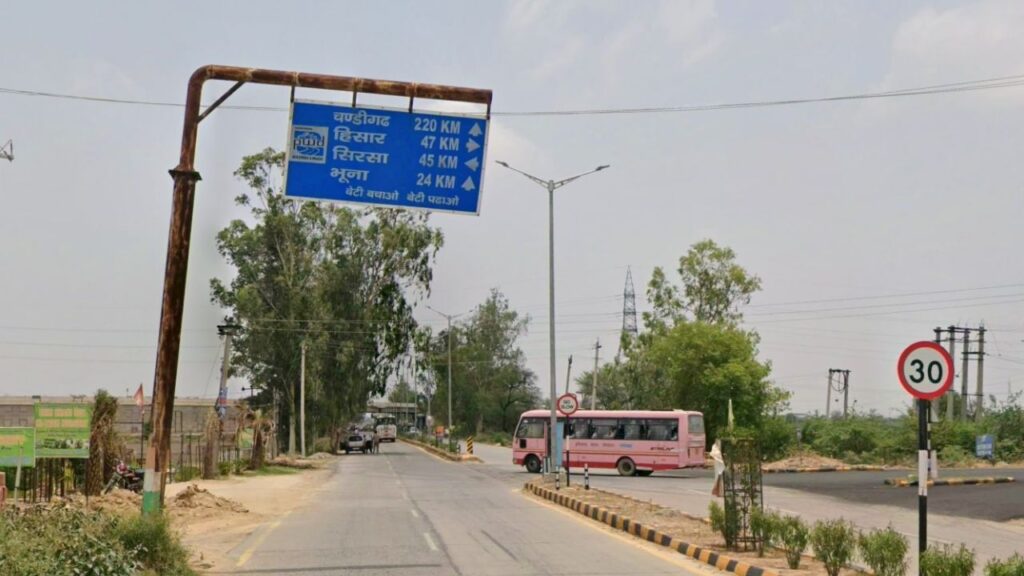 A state highway SH-2 route signboard to explore Haryana showing road distances toward Bhuna, Hisar, and Sirsa.