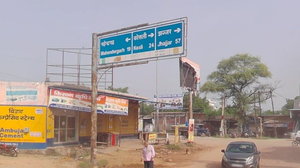 A state highway SH-24 signboard in Kanina town to explore Haryana showing the route distance toward Mahendragarh.