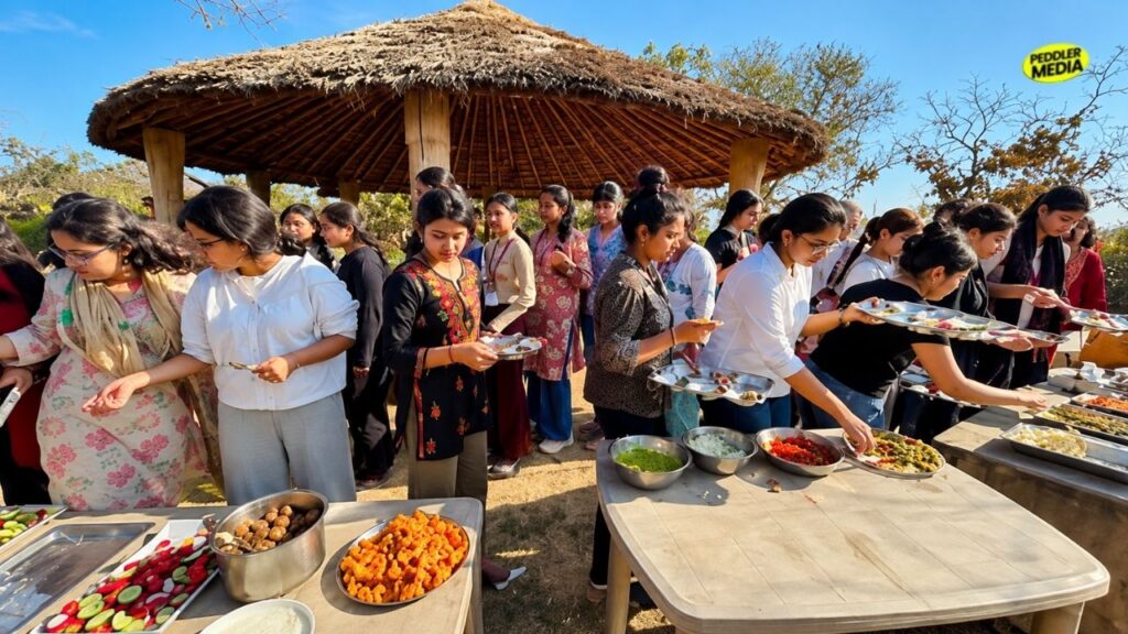 A large crowd of visitors lining up at an outdoor buffet stall to try authentic Haryanvi traditional food during the Rakhigarhi food festival.

